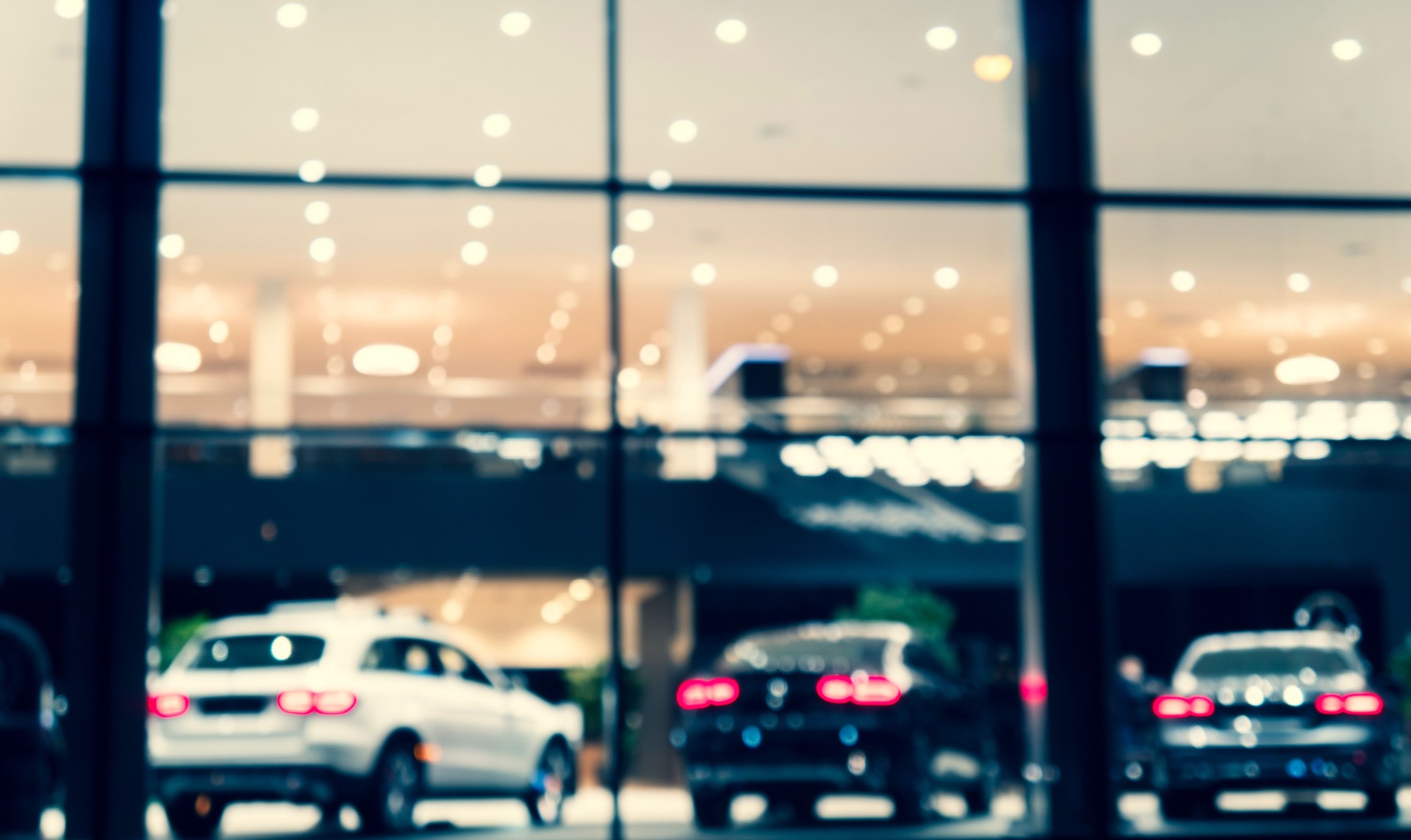 Blurred background with car dealership exterior. Abstract blurred photo of modern building motor showroom. Blur car show room office bokeh lights. Automobile retail shop